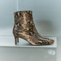 Women's brown snake print leather ankle boot with stiletto heel, pointed toe and gold buckle detailing